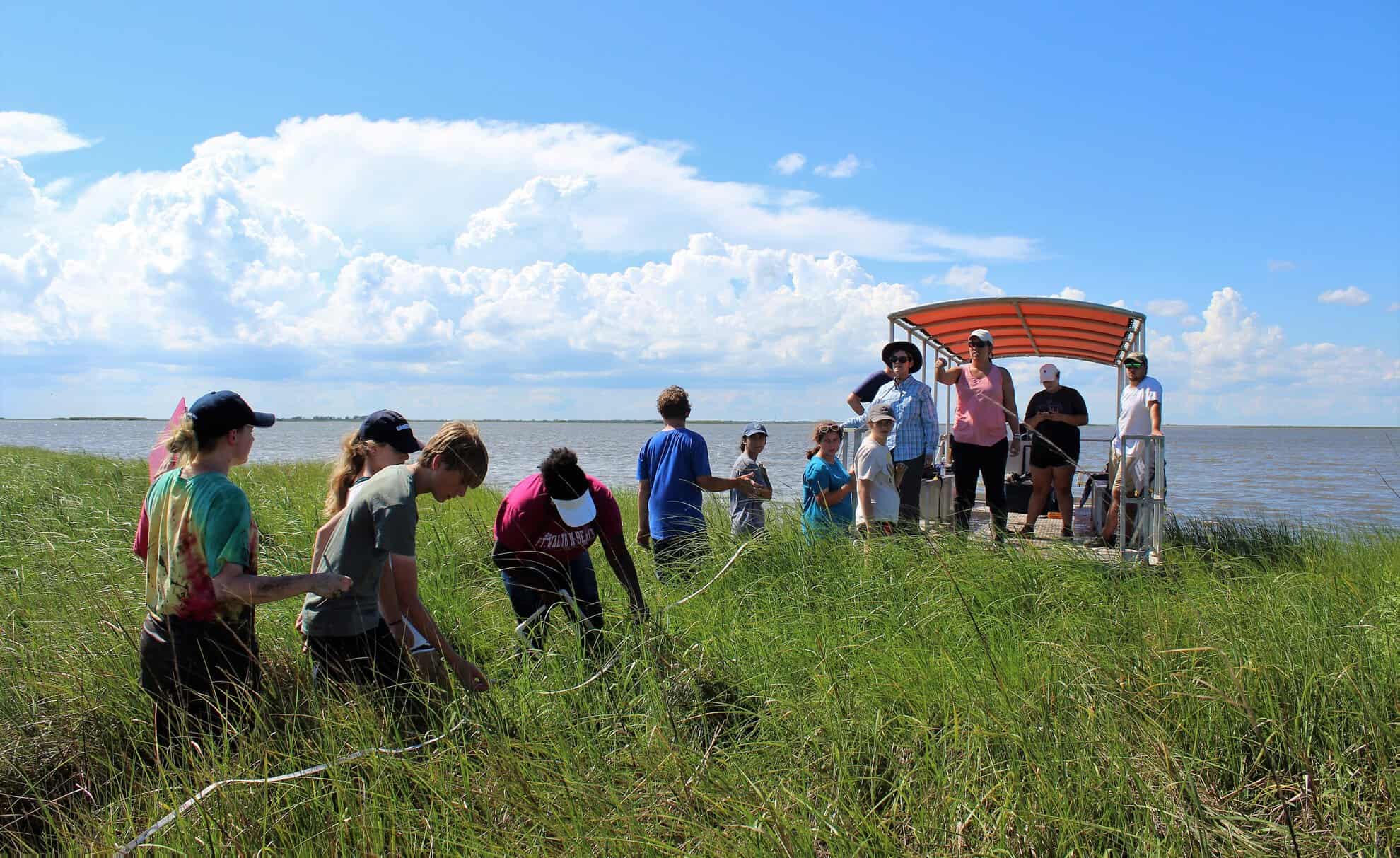 A group of people stepping off a boat to do an activity along a body of water