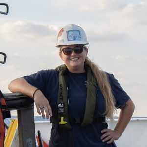 Young woman in safety gear smiling outdoors at LUMCON research site.