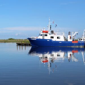 Research vessel docked at a calm water harbor with clear blue sky.