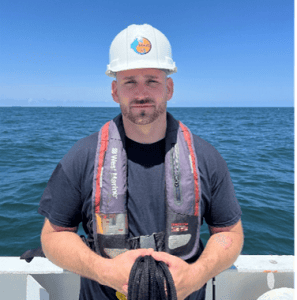 Man in safety gear on boat with ocean background at LUMCON.