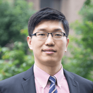 Portrait of Zhengchen (John) Zang in professional attire outdoors.