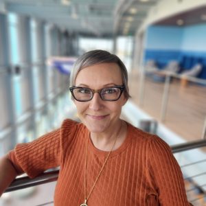 Smiling woman with glasses in a modern, bright building interior at LUMCON.
