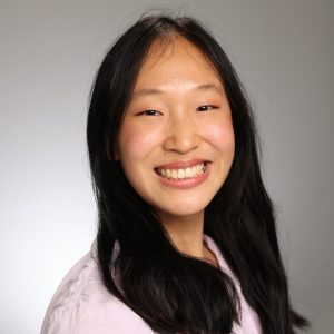 Smiling woman with long black hair in a professional portrait.