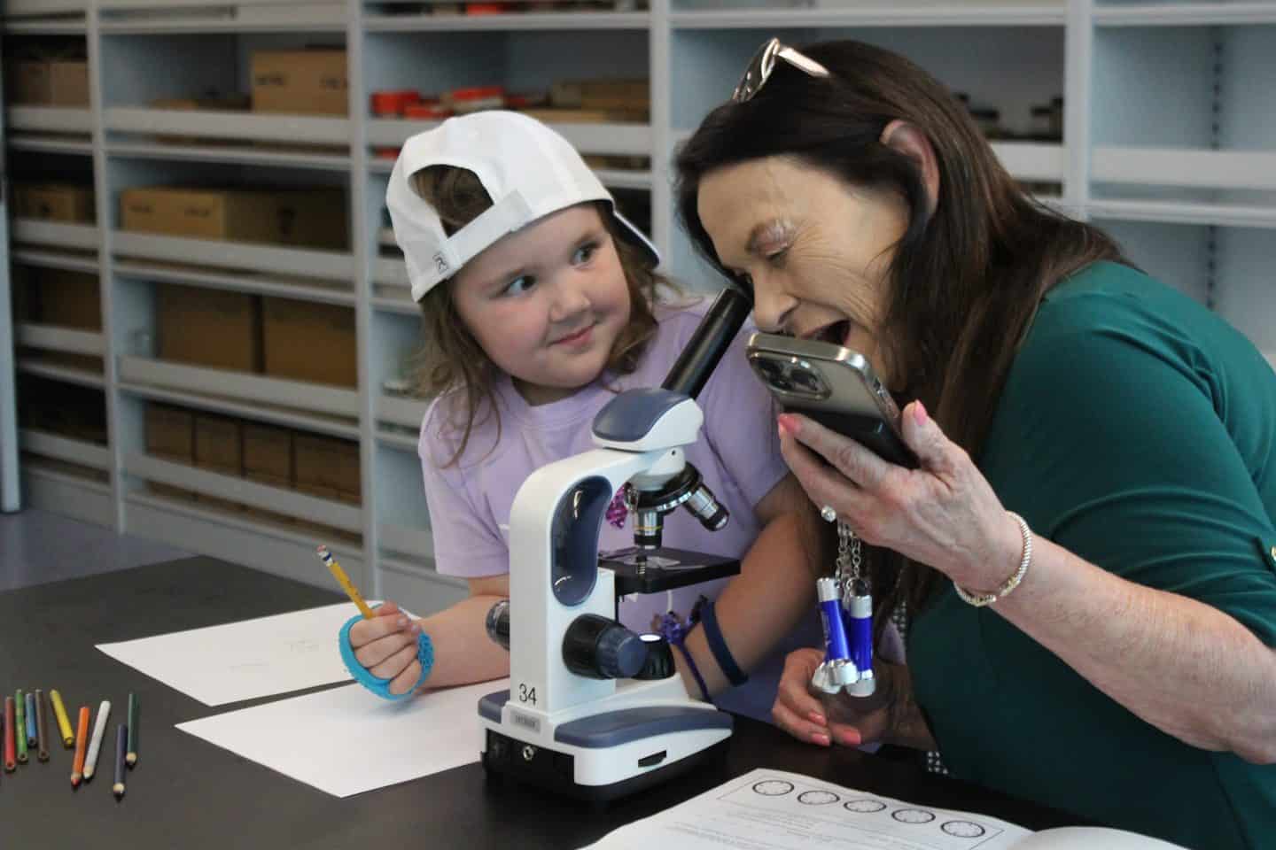 Adualt and child look through a microscope in a lab.